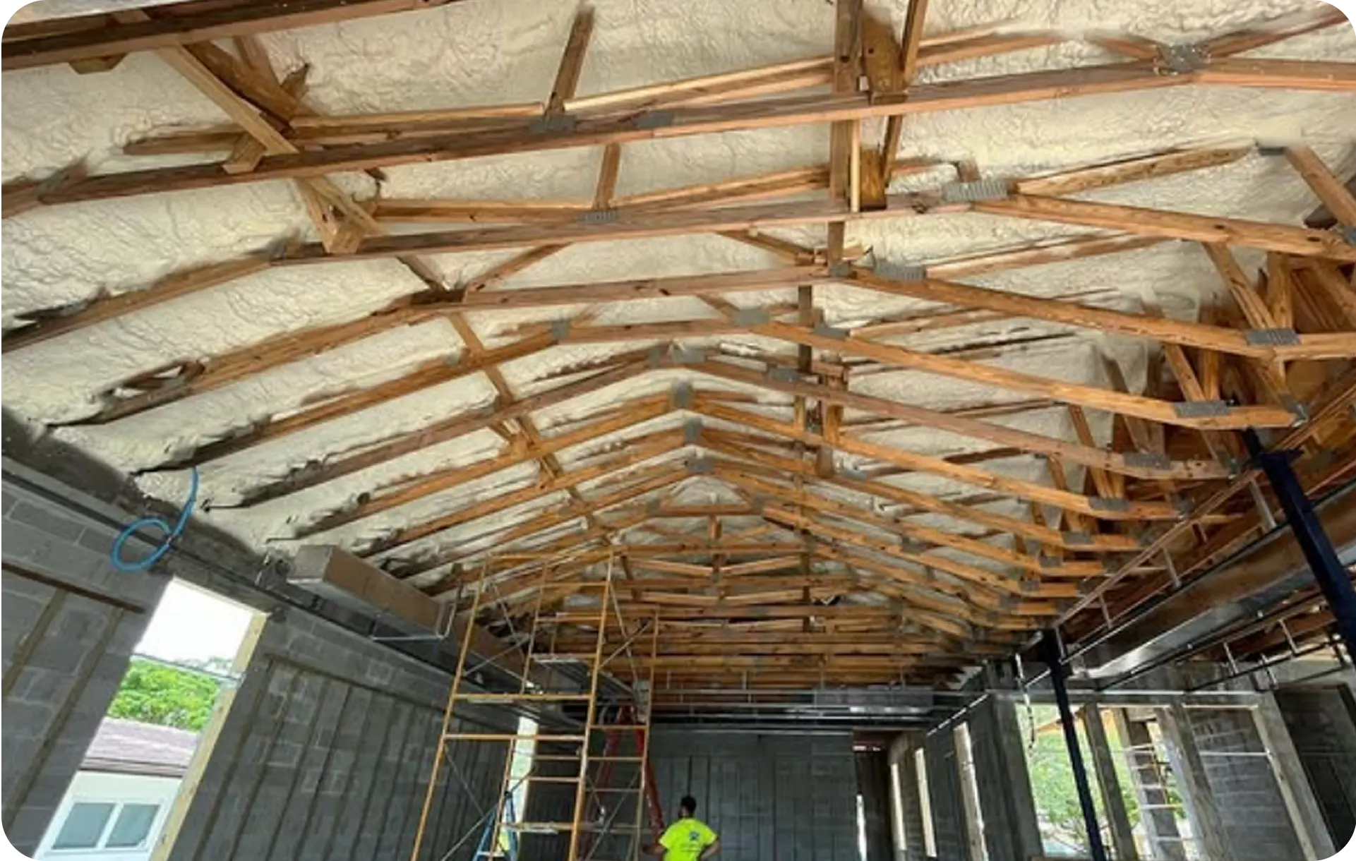 Closed-cell spray foam insulation applied to roof trusses during new construction in South Florida